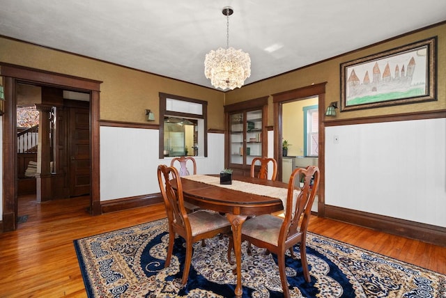 dining space with wood-type flooring, ornamental molding, and a chandelier