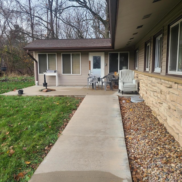 property entrance featuring a lawn and a patio area