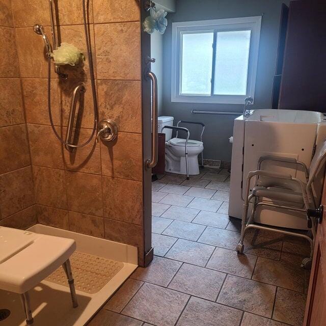 bathroom featuring tiled shower and toilet