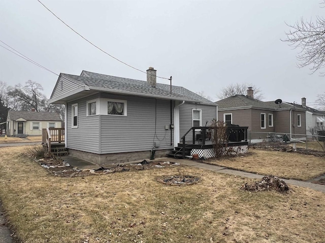 back of property with a wooden deck and a lawn