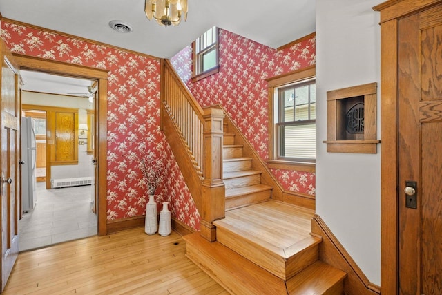 stairs with wallpapered walls, baseboards, visible vents, and hardwood / wood-style floors