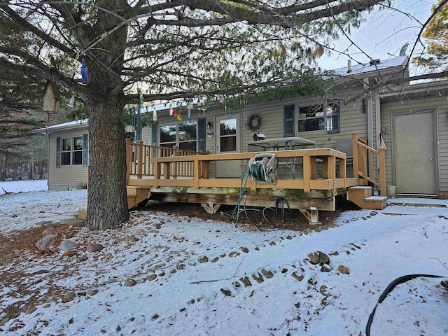 snow covered rear of property with a wooden deck