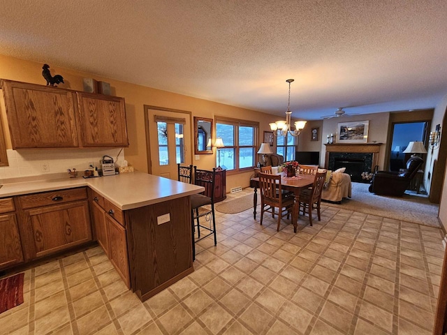 kitchen featuring a breakfast bar, a chandelier, a textured ceiling, kitchen peninsula, and pendant lighting