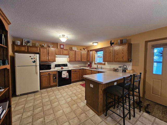 kitchen with sink, a breakfast bar area, electric range oven, kitchen peninsula, and white fridge