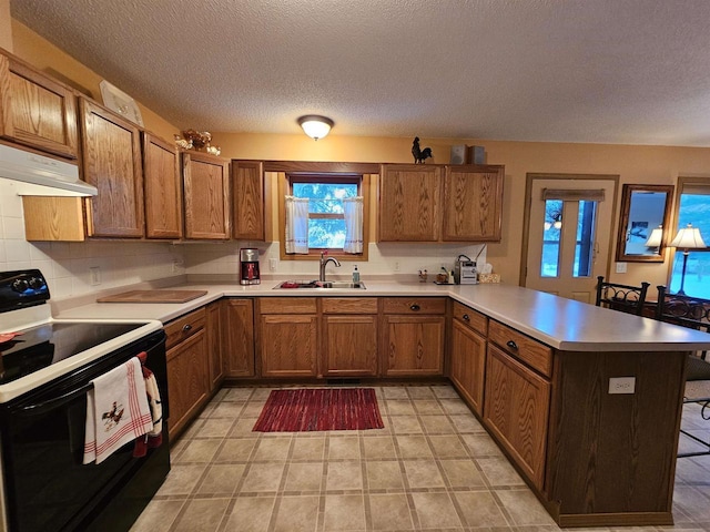 kitchen featuring sink, a breakfast bar area, backsplash, electric range, and kitchen peninsula