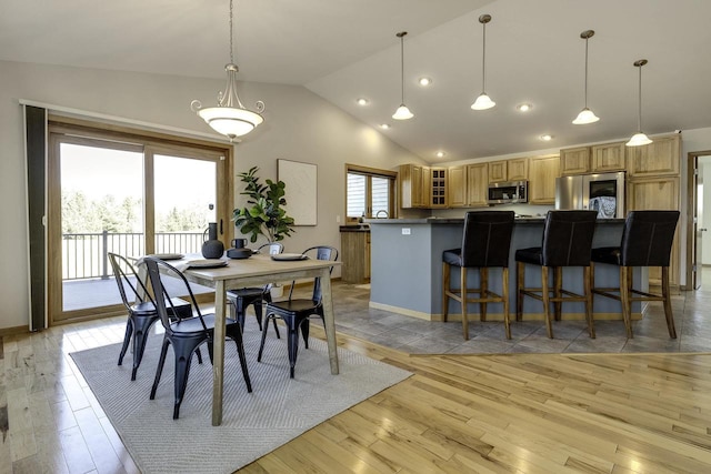 dining area featuring light hardwood / wood-style flooring and high vaulted ceiling