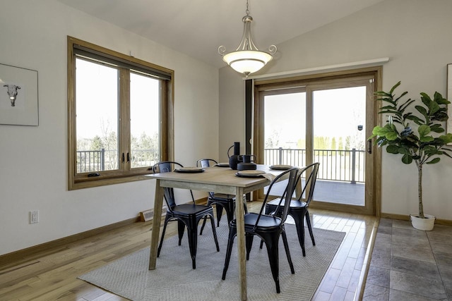 dining room with a healthy amount of sunlight, lofted ceiling, and wood-type flooring