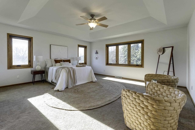 carpeted bedroom with ceiling fan and a raised ceiling