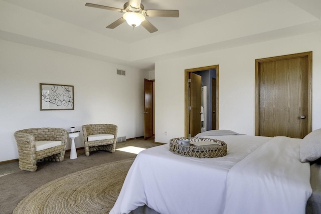 carpeted bedroom featuring a raised ceiling and ceiling fan