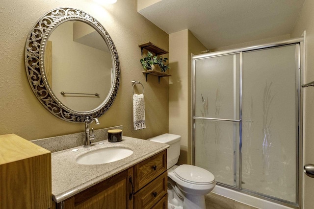 bathroom with vanity, a shower with shower door, and toilet