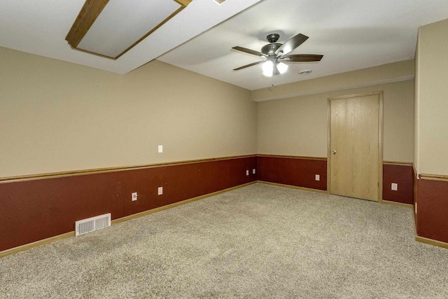 carpeted spare room featuring ceiling fan and wood walls