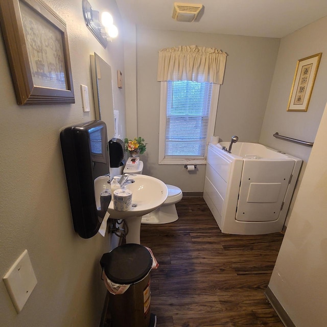 bathroom with sink, wood-type flooring, a bath, and toilet