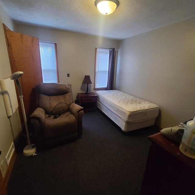 bedroom featuring dark carpet and a textured ceiling