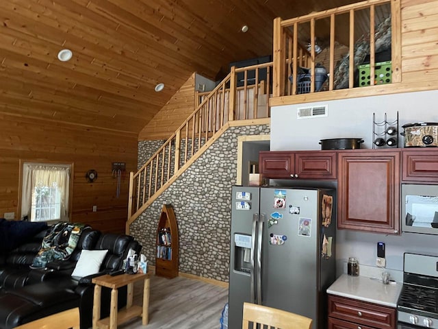 kitchen with wood ceiling, appliances with stainless steel finishes, hardwood / wood-style floors, vaulted ceiling, and wood walls