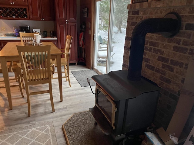 dining space with light hardwood / wood-style floors and a wood stove