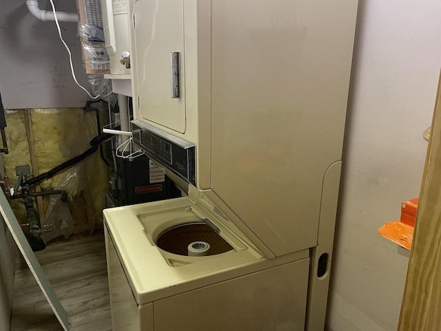 washroom with hardwood / wood-style floors and stacked washing maching and dryer