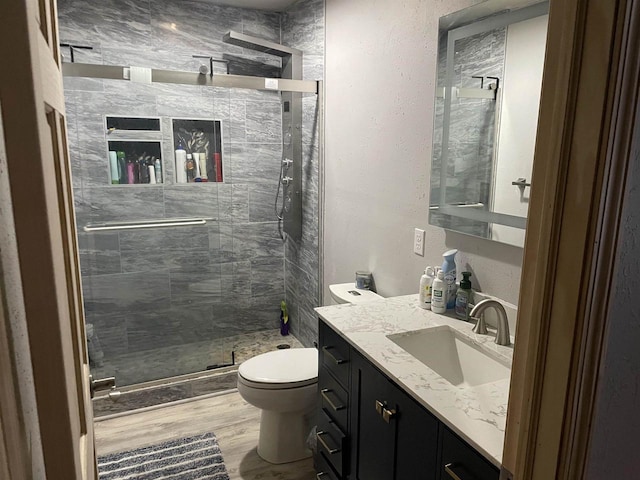 bathroom featuring vanity, toilet, a shower with shower door, and hardwood / wood-style floors