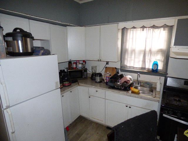 kitchen featuring hardwood / wood-style flooring, white cabinetry, sink, and black appliances