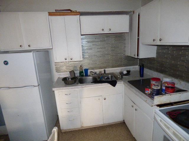 kitchen featuring tasteful backsplash, white cabinetry, sink, white fridge, and black electric cooktop