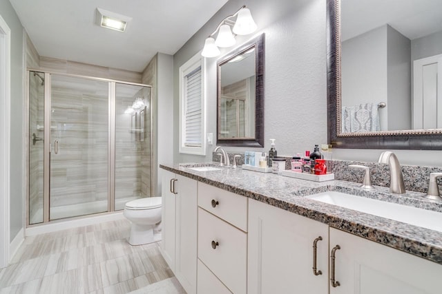 bathroom with vanity, toilet, and a shower with door