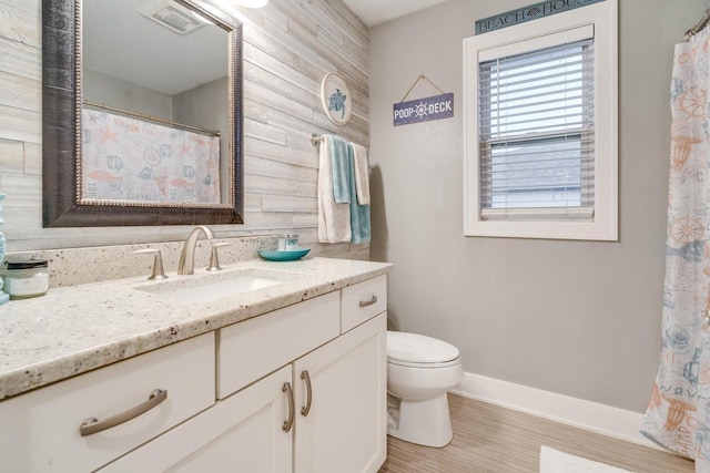 bathroom with vanity, toilet, wood-type flooring, and wood walls