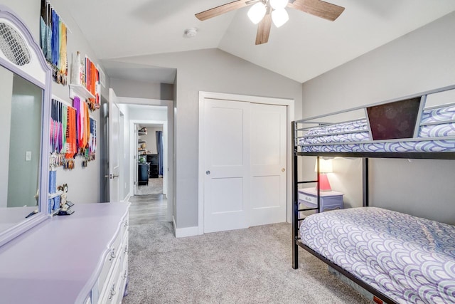 carpeted bedroom with ceiling fan, vaulted ceiling, and a closet