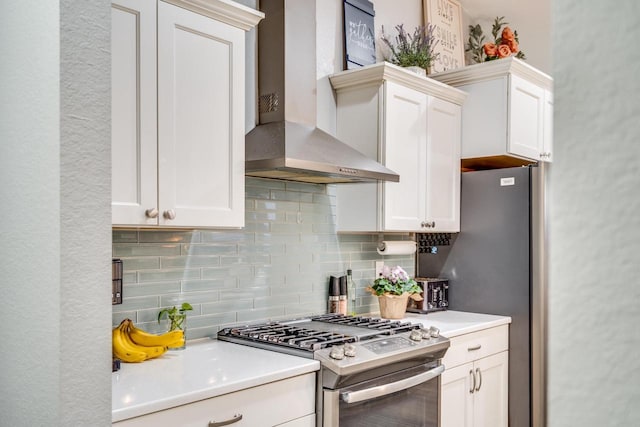 kitchen with white cabinetry, stainless steel gas range oven, wall chimney range hood, and backsplash