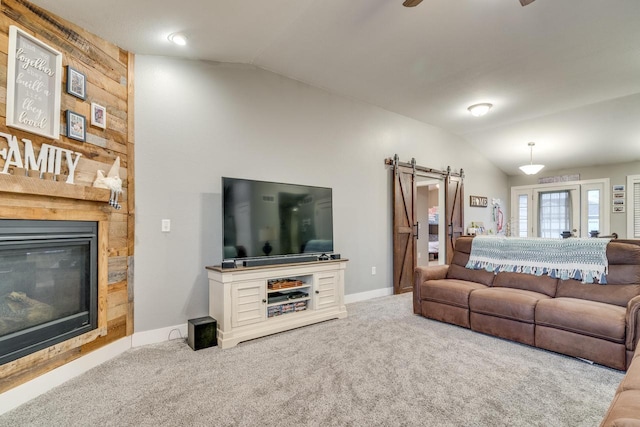 carpeted living room featuring ceiling fan, a fireplace, lofted ceiling, and a barn door