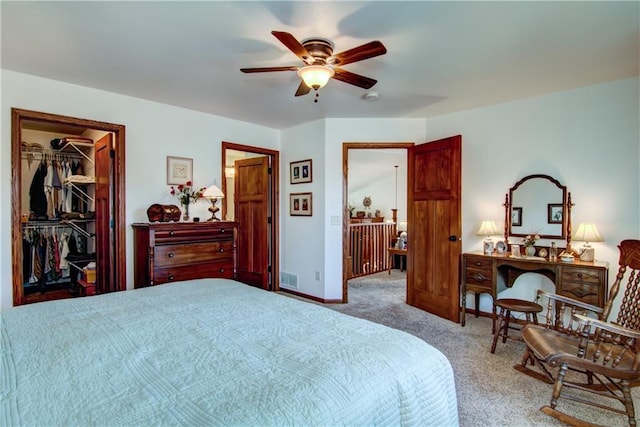 bedroom featuring a spacious closet, light carpet, ceiling fan, and a closet