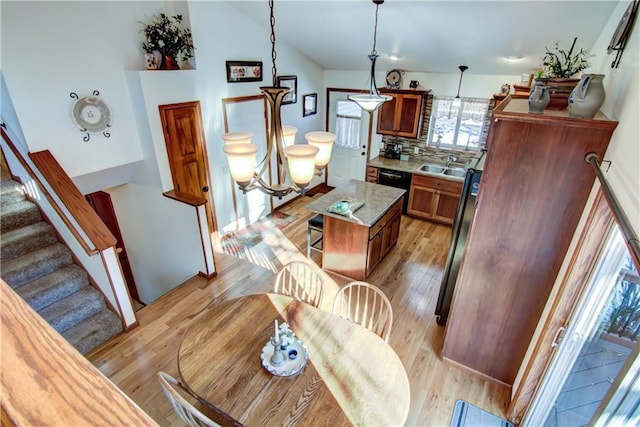 kitchen with lofted ceiling, sink, decorative light fixtures, a center island, and light wood-type flooring