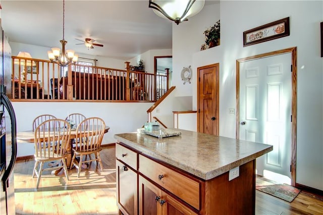 kitchen with decorative light fixtures, light hardwood / wood-style floors, a chandelier, and a kitchen island