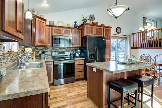 kitchen with lofted ceiling, sink, stainless steel appliances, a center island, and decorative light fixtures