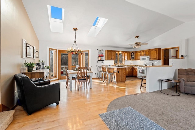 living room with ceiling fan with notable chandelier, light hardwood / wood-style flooring, and high vaulted ceiling