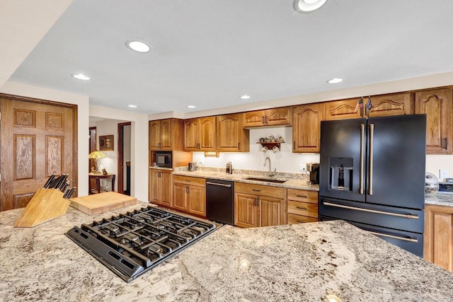 kitchen featuring light stone counters, sink, and black appliances