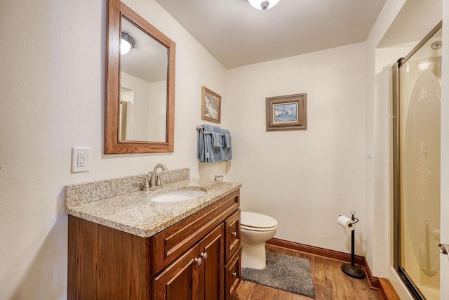 bathroom with vanity, hardwood / wood-style floors, a shower with door, and toilet