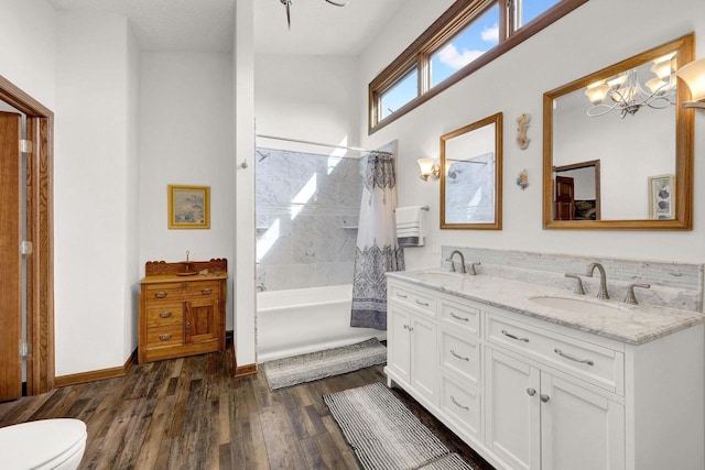 full bathroom featuring hardwood / wood-style flooring, shower / tub combo, vanity, a notable chandelier, and toilet