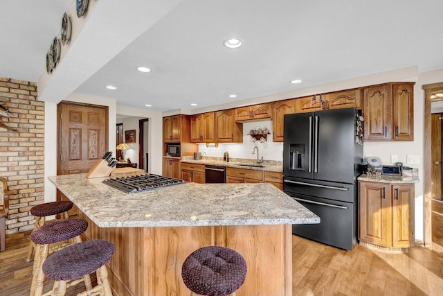 kitchen with a spacious island, a kitchen bar, sink, and black appliances