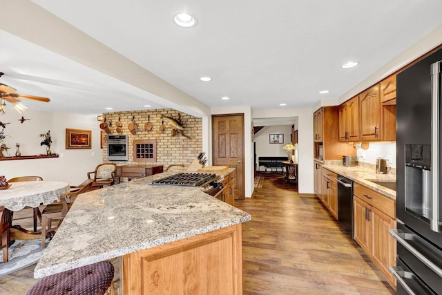 kitchen with a kitchen island, dishwasher, light stone countertops, fridge with ice dispenser, and light hardwood / wood-style flooring