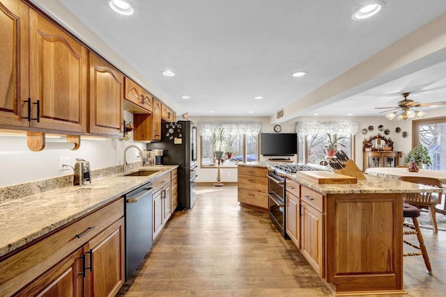 kitchen featuring sink, stainless steel appliances, a kitchen breakfast bar, and light stone countertops