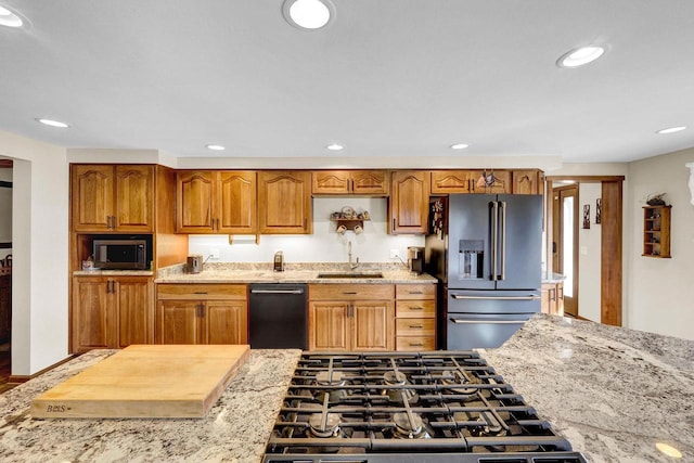 kitchen with sink, light stone countertops, and appliances with stainless steel finishes