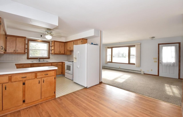 kitchen featuring sink, light wood-type flooring, backsplash, a baseboard heating unit, and white appliances