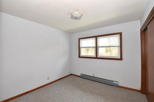 spare room with carpet floors and a baseboard heating unit