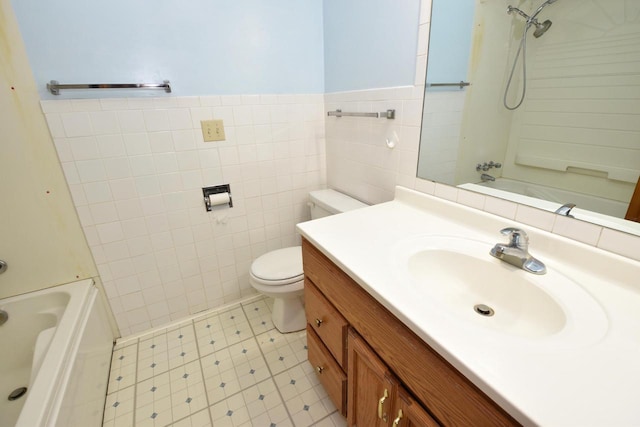 full bathroom with vanity, toilet, tiled shower / bath combo, and tile walls