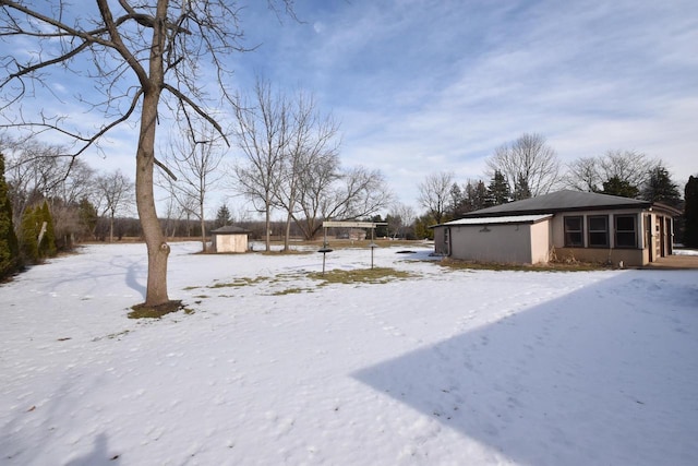 snowy yard featuring a storage unit