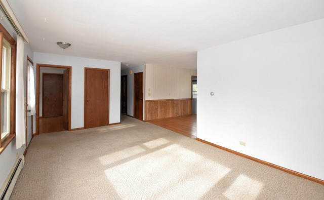 empty room featuring light colored carpet and baseboard heating