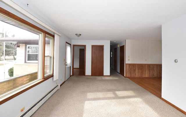 carpeted empty room with a baseboard heating unit