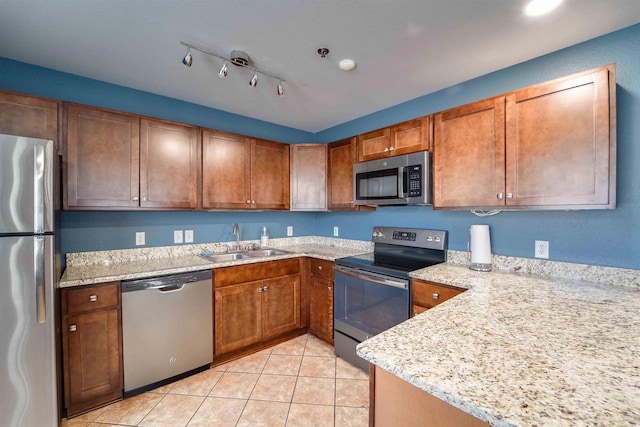 kitchen featuring light tile patterned flooring, stainless steel appliances, sink, and light stone counters