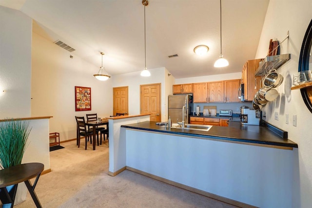 kitchen with appliances with stainless steel finishes, sink, light colored carpet, and decorative light fixtures