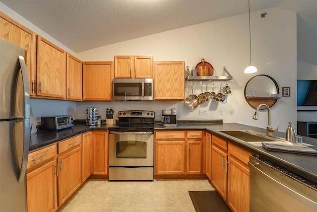 kitchen featuring sink, stainless steel appliances, a textured ceiling, decorative light fixtures, and vaulted ceiling