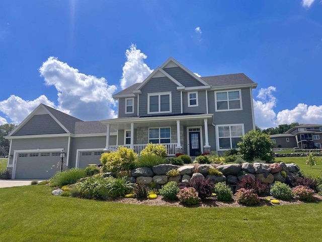 craftsman inspired home featuring a porch, a front yard, and an attached garage